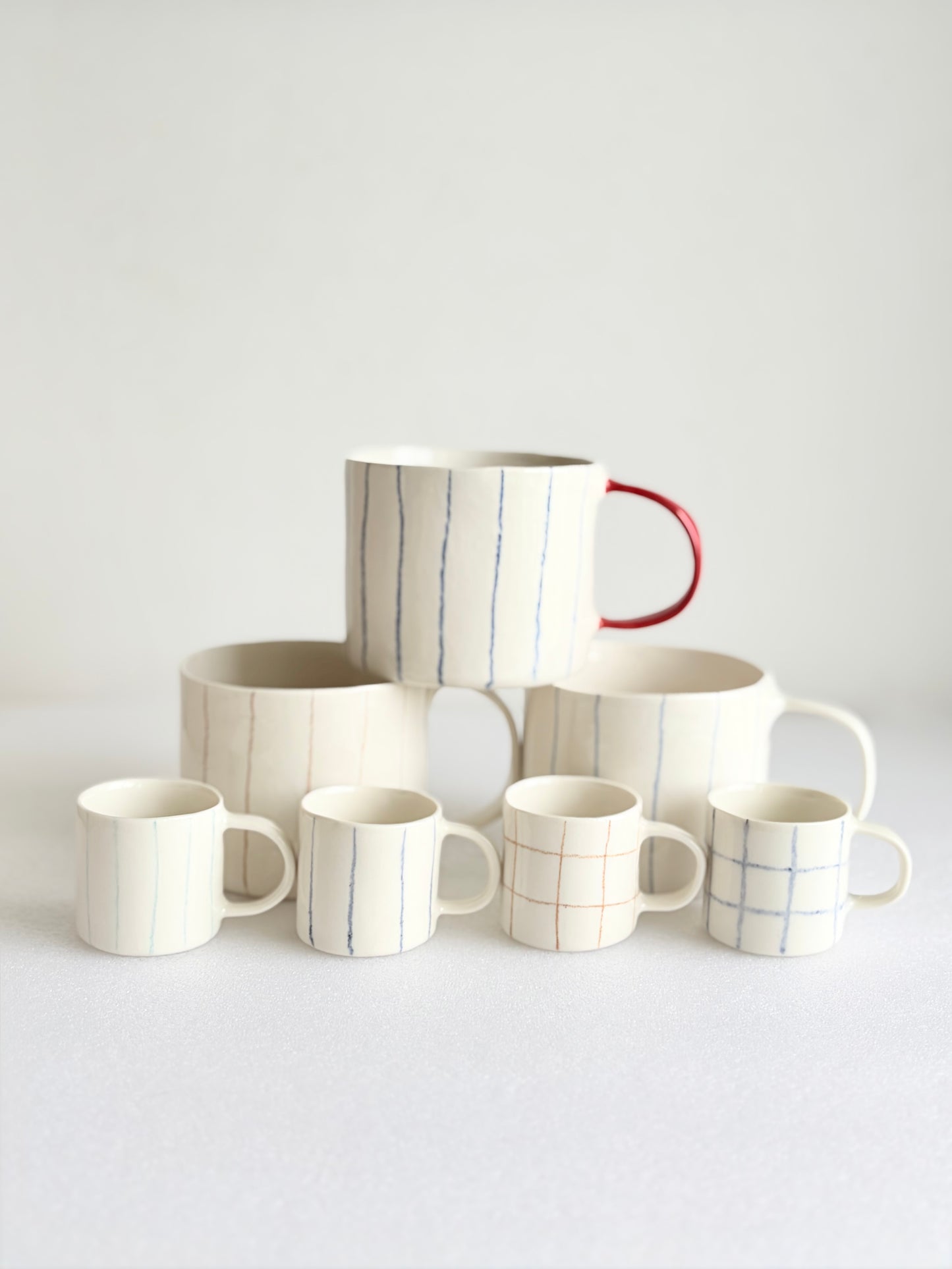 Kubek porcelanowy w pasy z czerwonym uchem