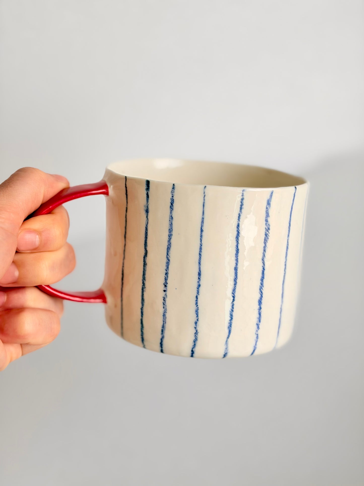 Kubek porcelanowy w pasy z czerwonym uchem