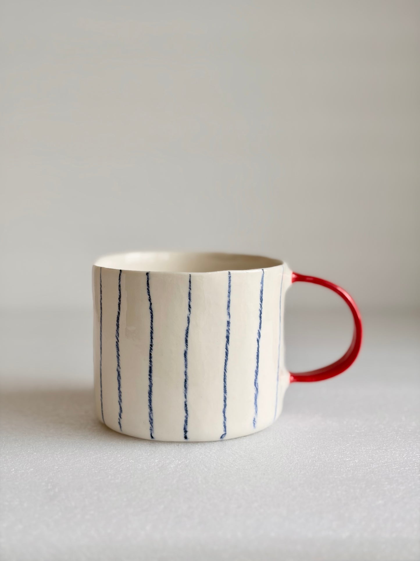Kubek porcelanowy w pasy z czerwonym uchem