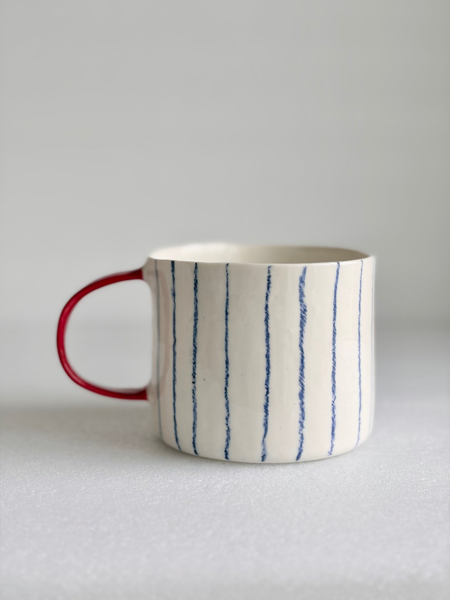 Kubek porcelanowy w pasy z czerwonym uchem