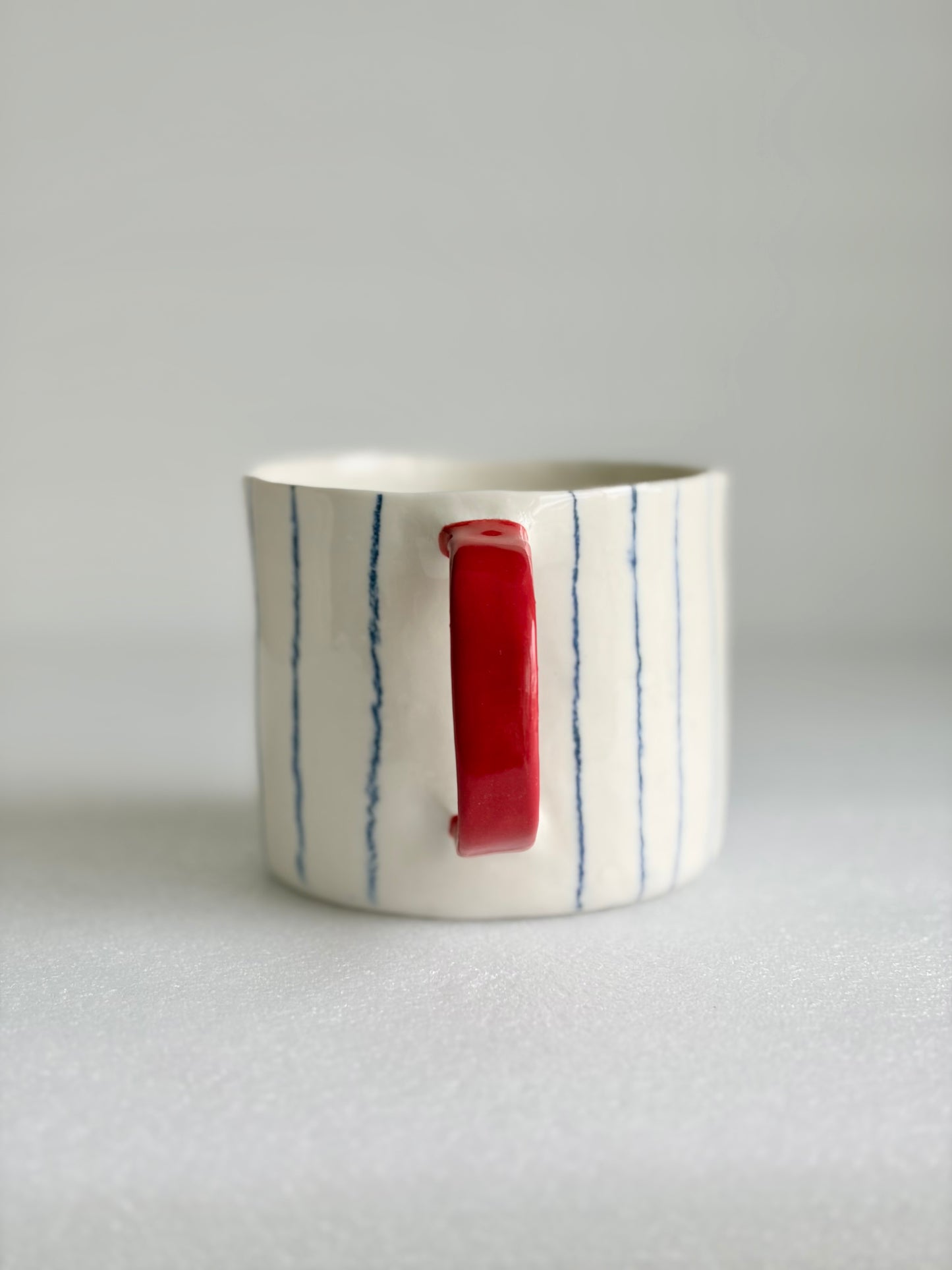 Kubek porcelanowy w pasy z czerwonym uchem